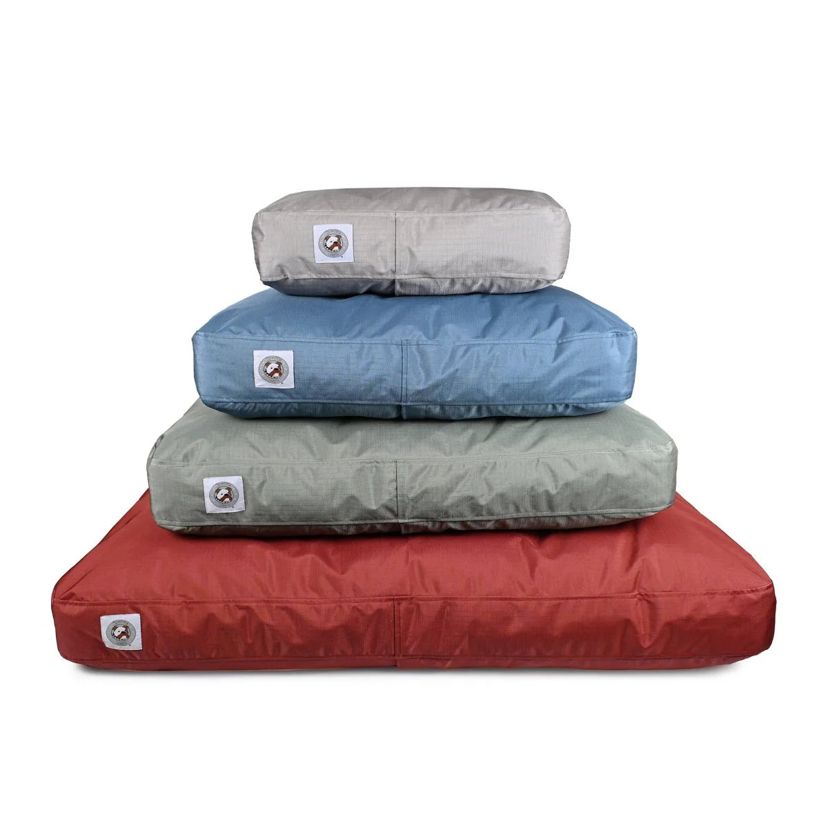 Stack of four dog beds in red, gray, blue, and beige on a white background