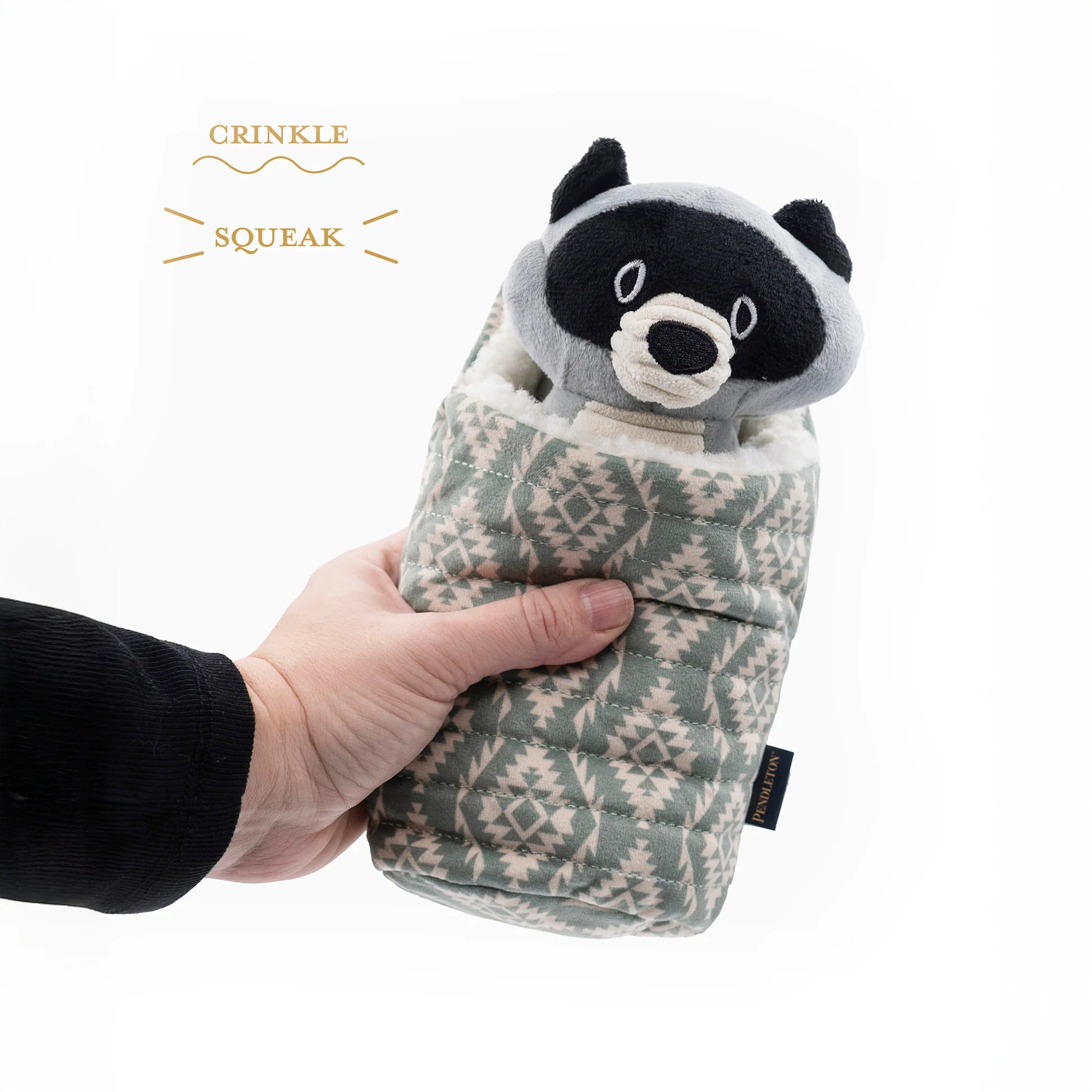 Plush raccoon toy with crinkle and squeak features held by a hand on a white background