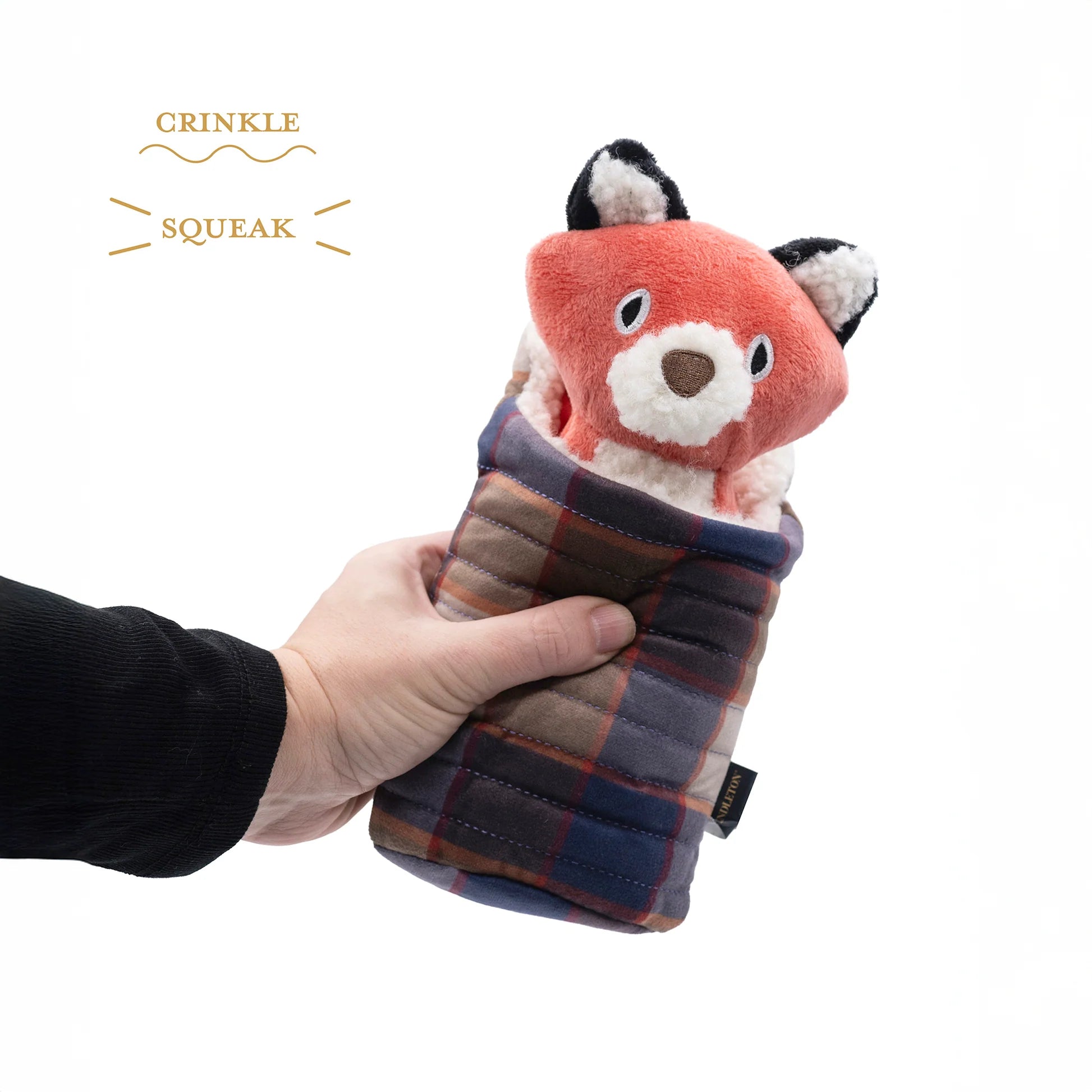 Hand holding a plush fox toy wrapped in plaid fabric with 'Crinkle Squeak' text above.