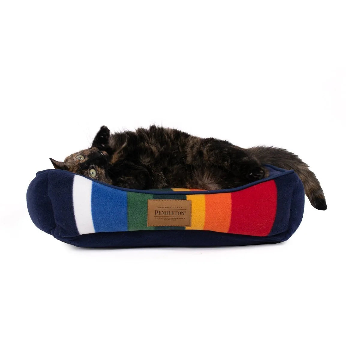 Cat lying on a colorful striped pet bed with Pendleton branding on a white background