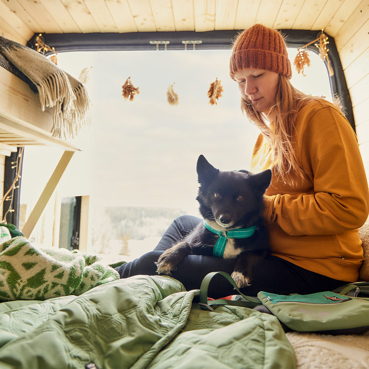 Woman sitting inside a van with a dog, surrounded by cozy decor.